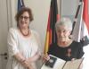 Dr. Ina Czyborra (l.) und Dr. Adriane Feustel (r.) mit der Urkunde und dem Verdienstkreuz am Bande, frontal. 